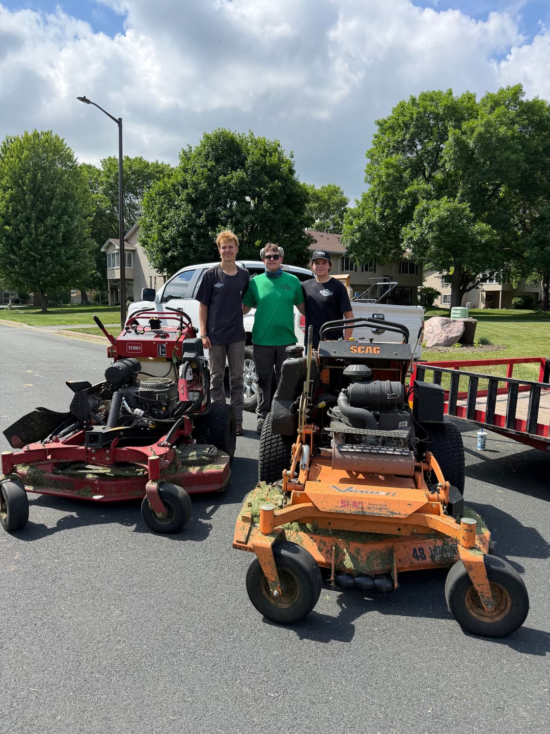 Lawn care team with riding mowers in residential area, ready for landscaping duties.